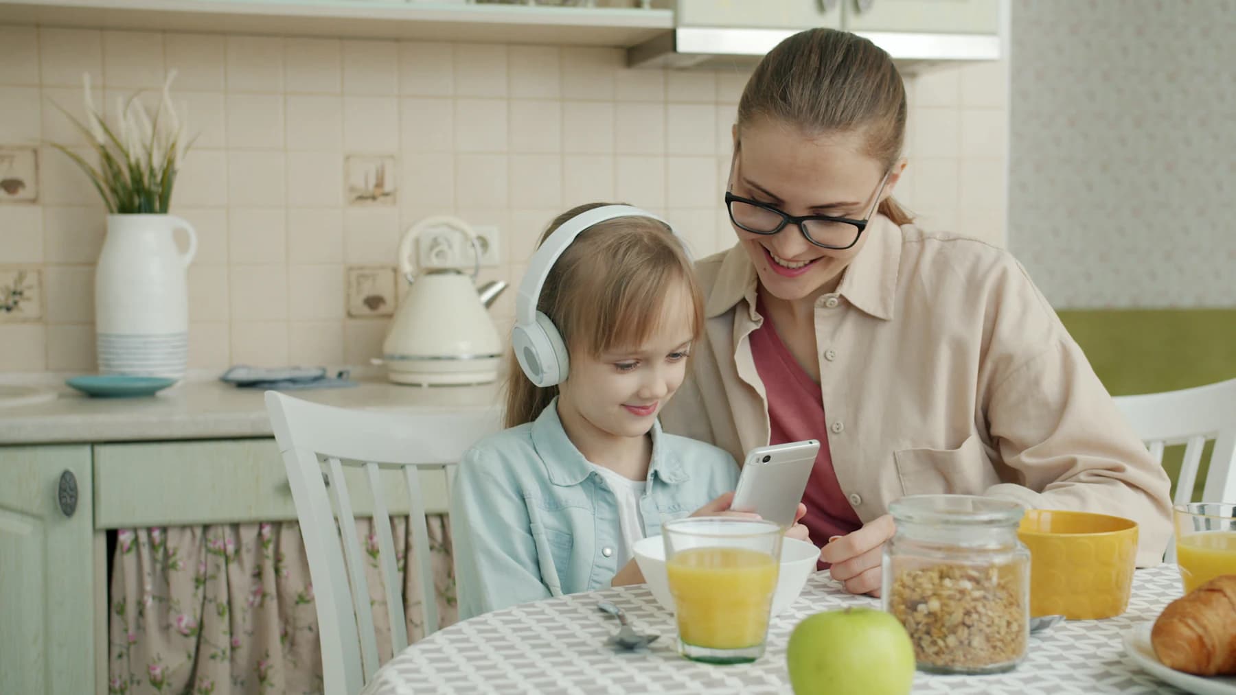 Une mère et sa fille prennent le petit-déjeuner avec un téléphone